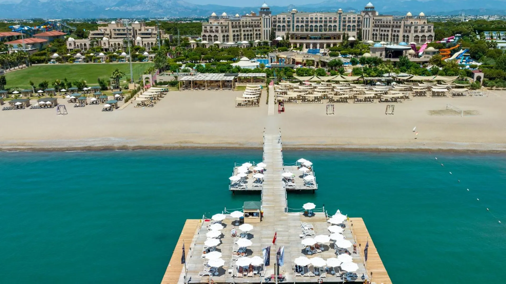 Spice Hotel & Spa Belek Exterior photo This is a high-angle, aerial photograph showcasing a large resort area situated along a beautiful coastline on a sunny day.

In the foreground, there is a clear, turquoise body of water, likely the ocean or a sea. Extending from the shore into this w